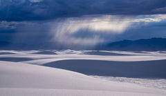 Dune Rain – fine art photograph of a rain shaft falling over mountains beyond the white dunes of White Sands National Park, New Mexico, by Aaron Chang