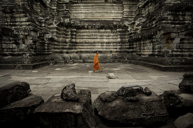 A lone monk walks along the ancient temples of Angkor Watt.