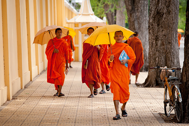 Monks walk along the Mekong river at dusk.